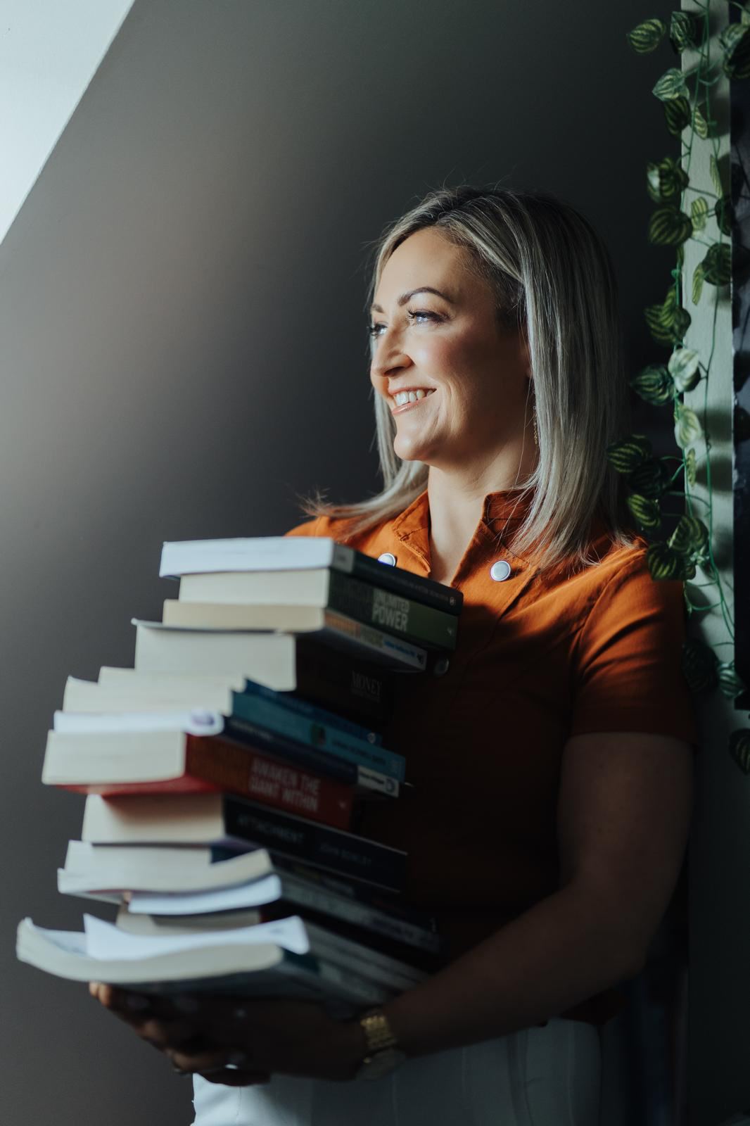 Maria Morgan, founder of Appreciating You, smiling and holding a stack of counselling books