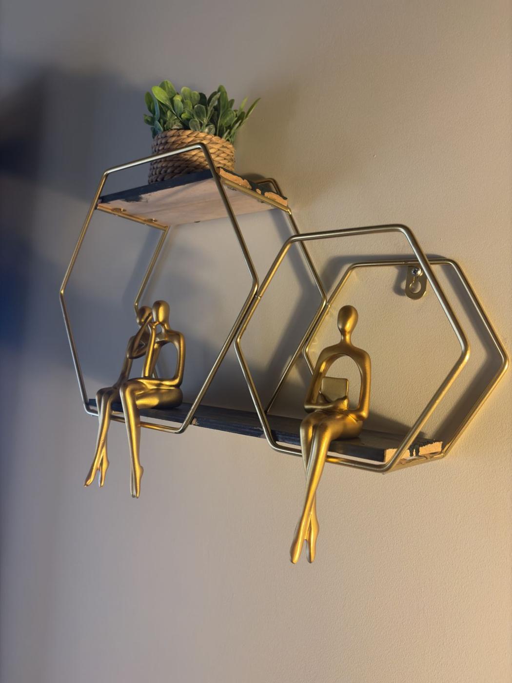 Gold figurines sitting in reflection on a hexagonal shelf